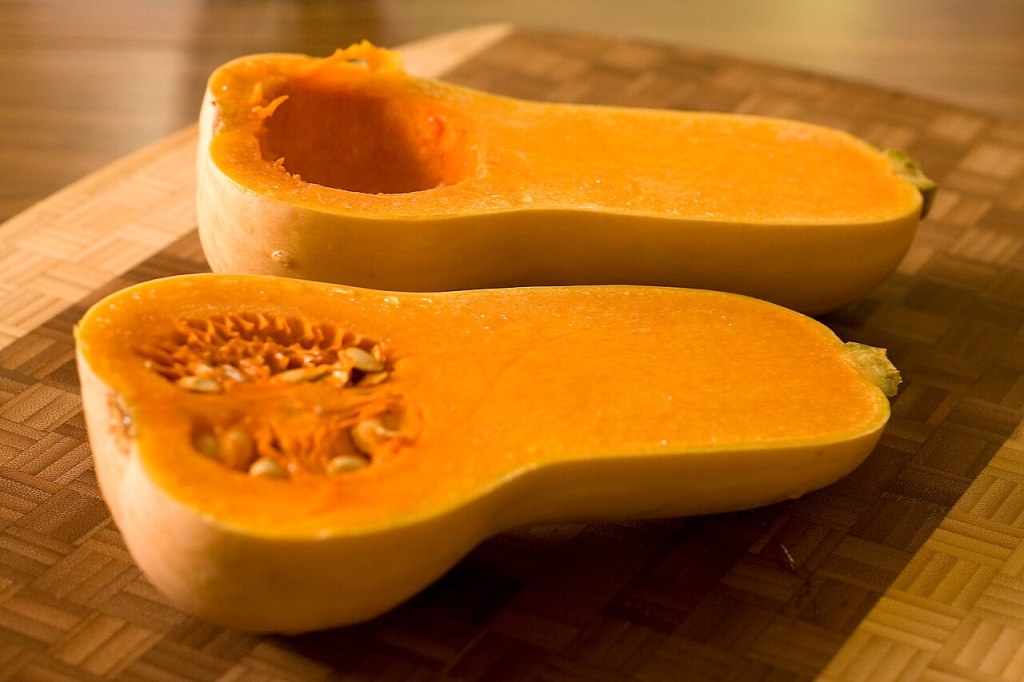 Calabaza cacahuete cortada por la mitad, con la carne naranja y las semillas