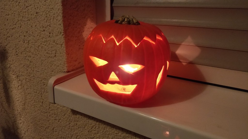 Calabaza de Halloween tallada e iluminada en una ventana