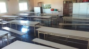 Comedor escolar vacío con mesas y bancos alargados