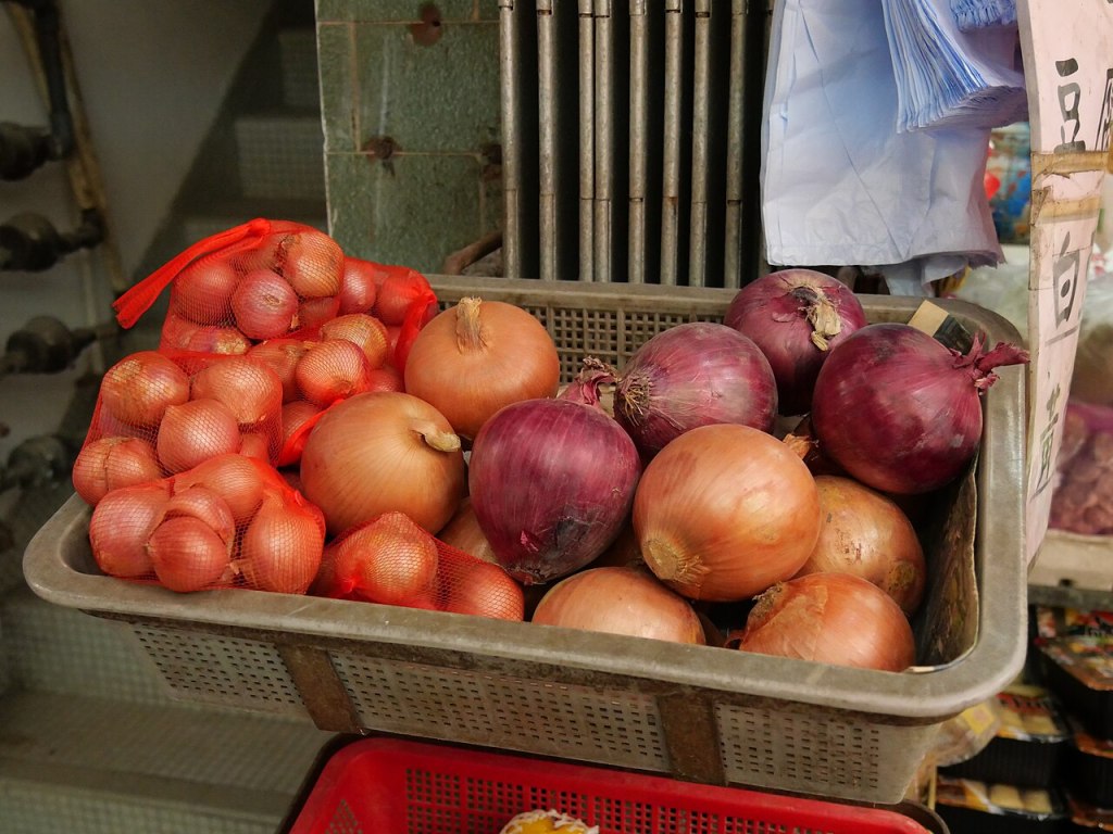 Cesta con cebollas amarillas, cebollas moradas y chalotas en un mercado